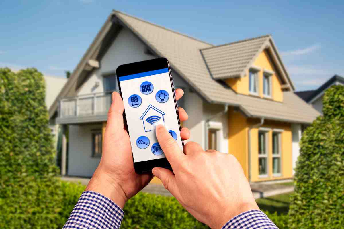 mano su controller del telefono per la smart hone e casa sullo sfondo