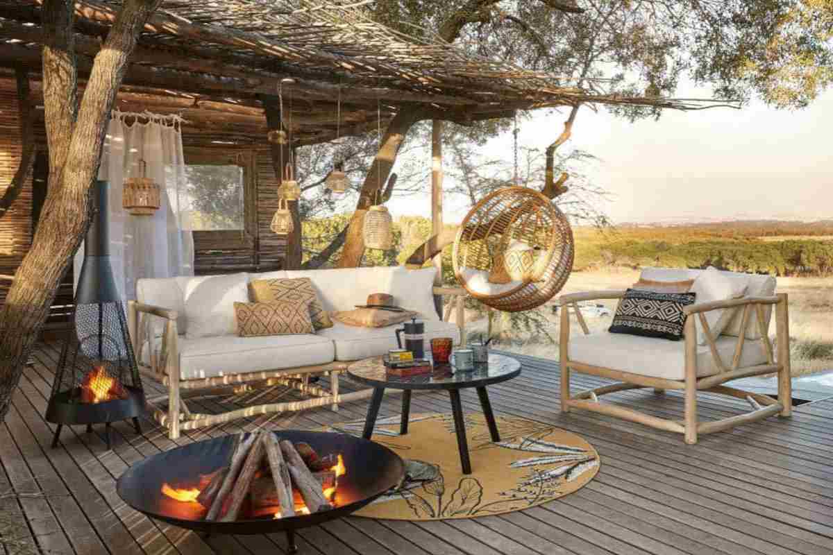 patio arredato con mobili del catalogo giardino Maisons du Monde, salottino in bambù, bracieri in metallo, poltrona sospesa, tappetto e tavolino