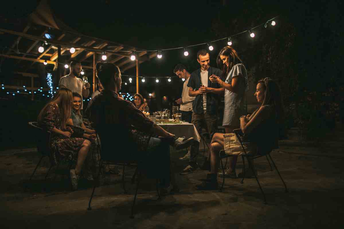 amici intorno al tavolo illuminato in giardino
