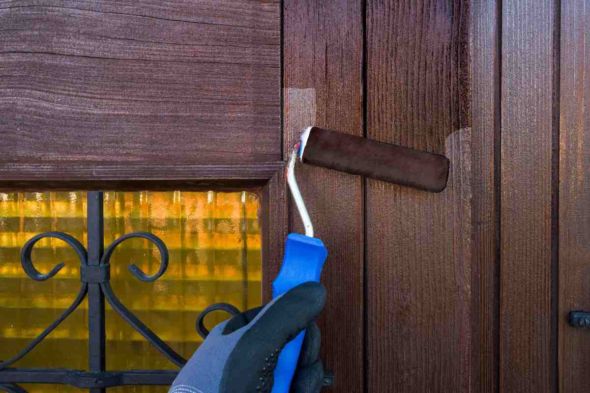 mano con rullo dipinge la porta in legno