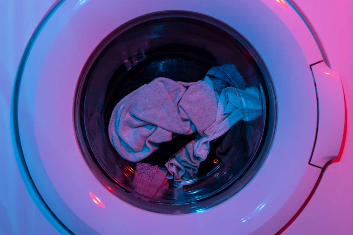 l'oblò di una lavatrice in azione con all'interno dei vestiti