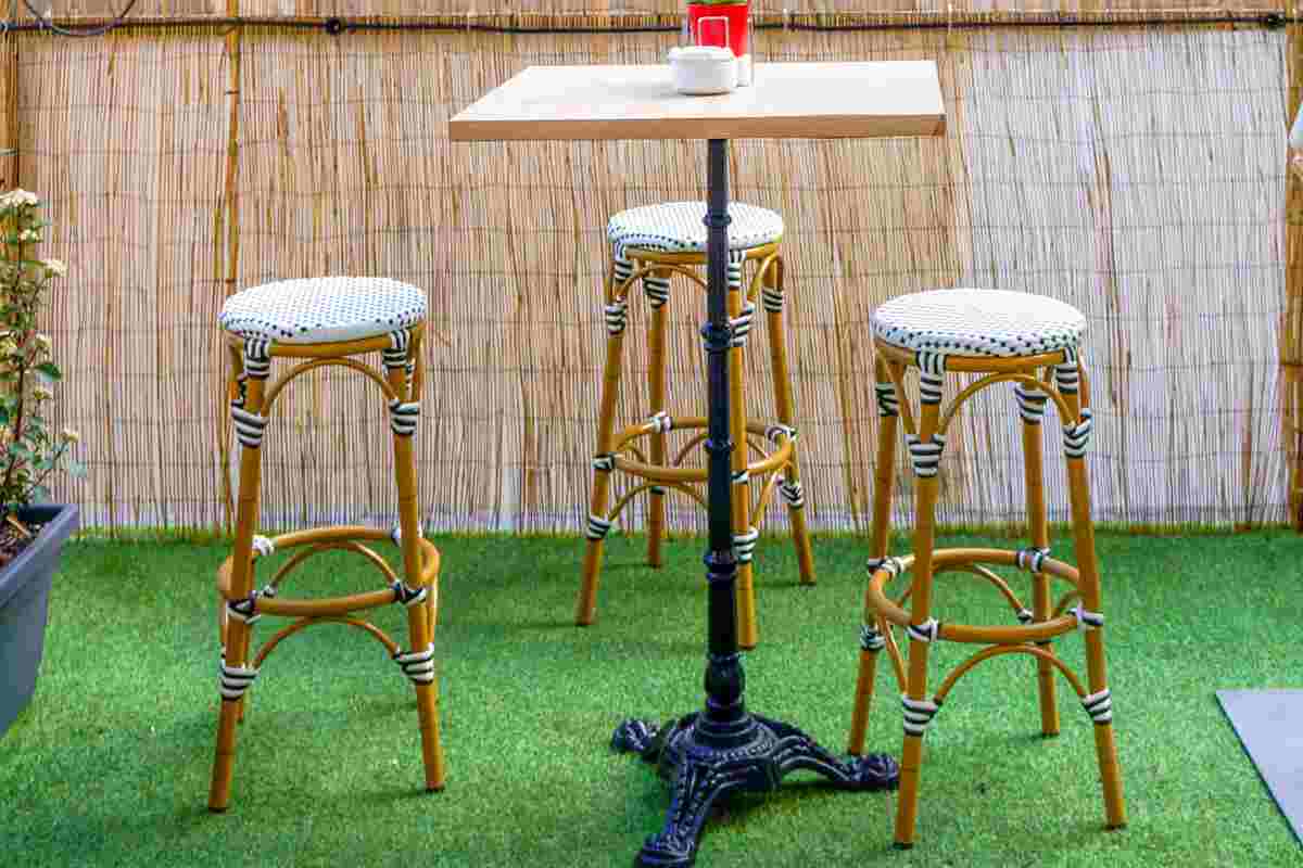 Erba sintetica sul terrazzo arredato con tavolo e sgabelli