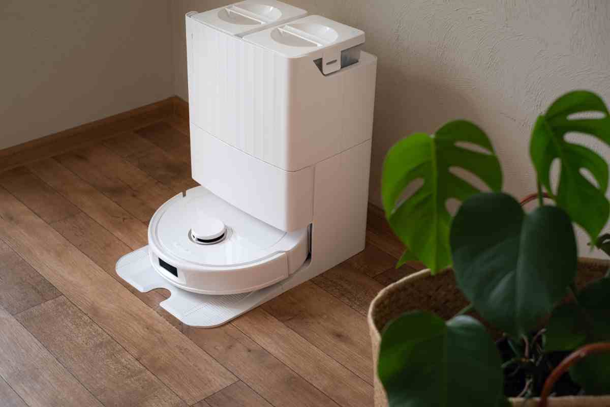 un robot lavapavimenti in un angolo della stanza con una pianta vicino