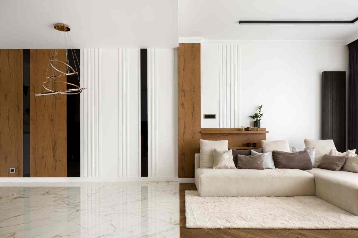 esempio di come arredare casa stile minimal, con divano angolare sulla parete nei colori neutri ed elementi architettonici in legno