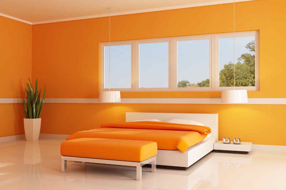 Camera da letto con parete arancione, panca e biancheria arancione