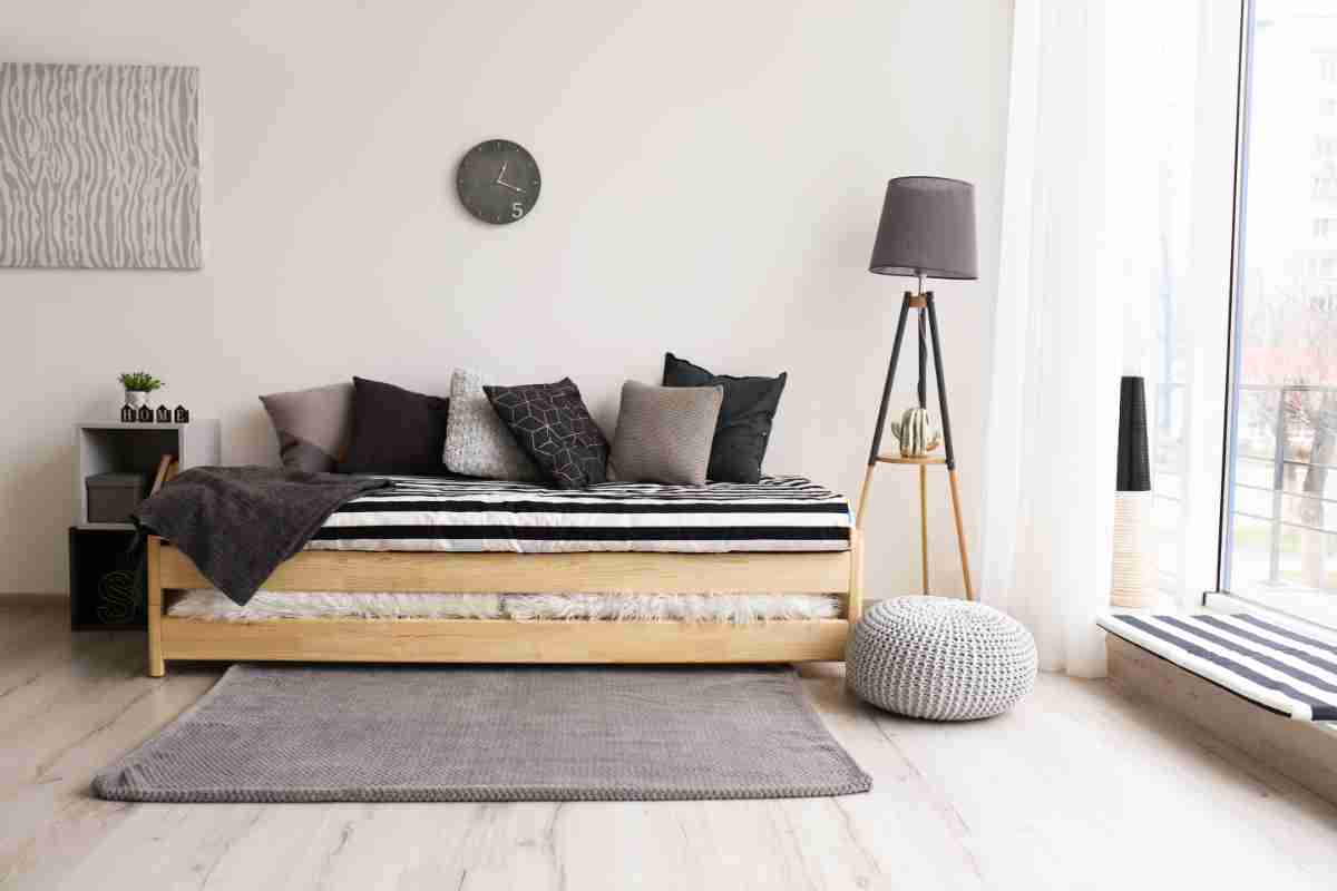 letto con struttura in legno, biancheria e cuscini neri