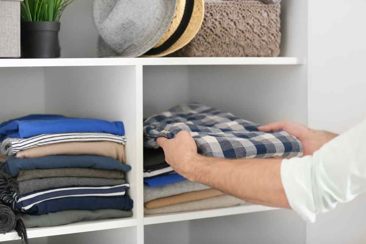 uomo mette in ordine i capi di abbigliamento in un armadio