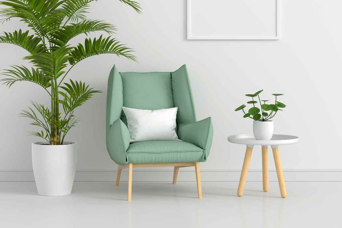angolo soggiorno con poltrona verde salvia, pianta grande e tavolino in legno con ripiano bianco