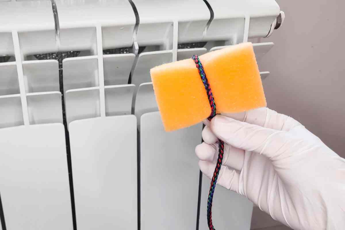 spugnetta con corda in mano a una persona per pulire i termosifoni