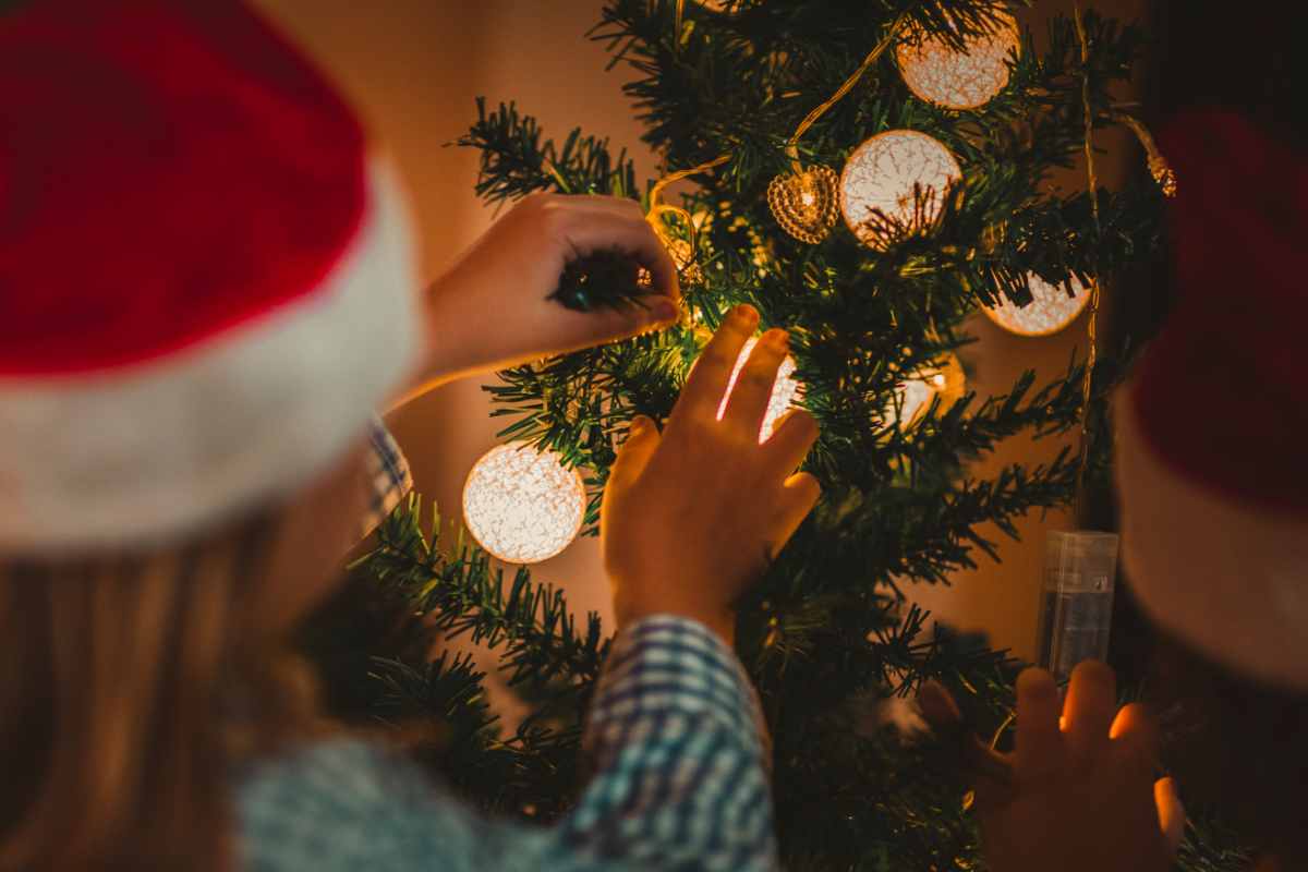 ragazzi addobbano l'albero di Natale posto a una certa altezza