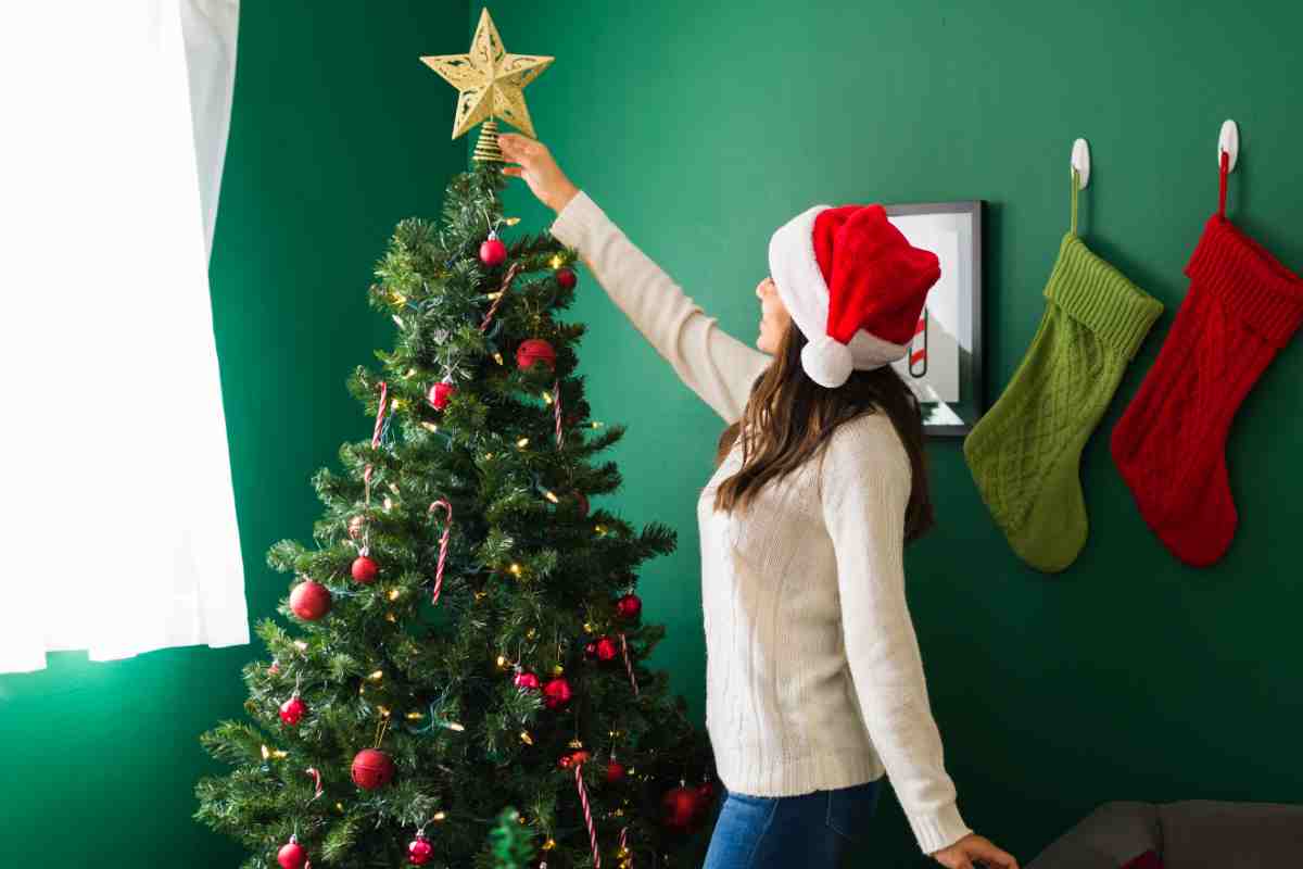 ragazza mette un puntale a stella sull'albero di Natale