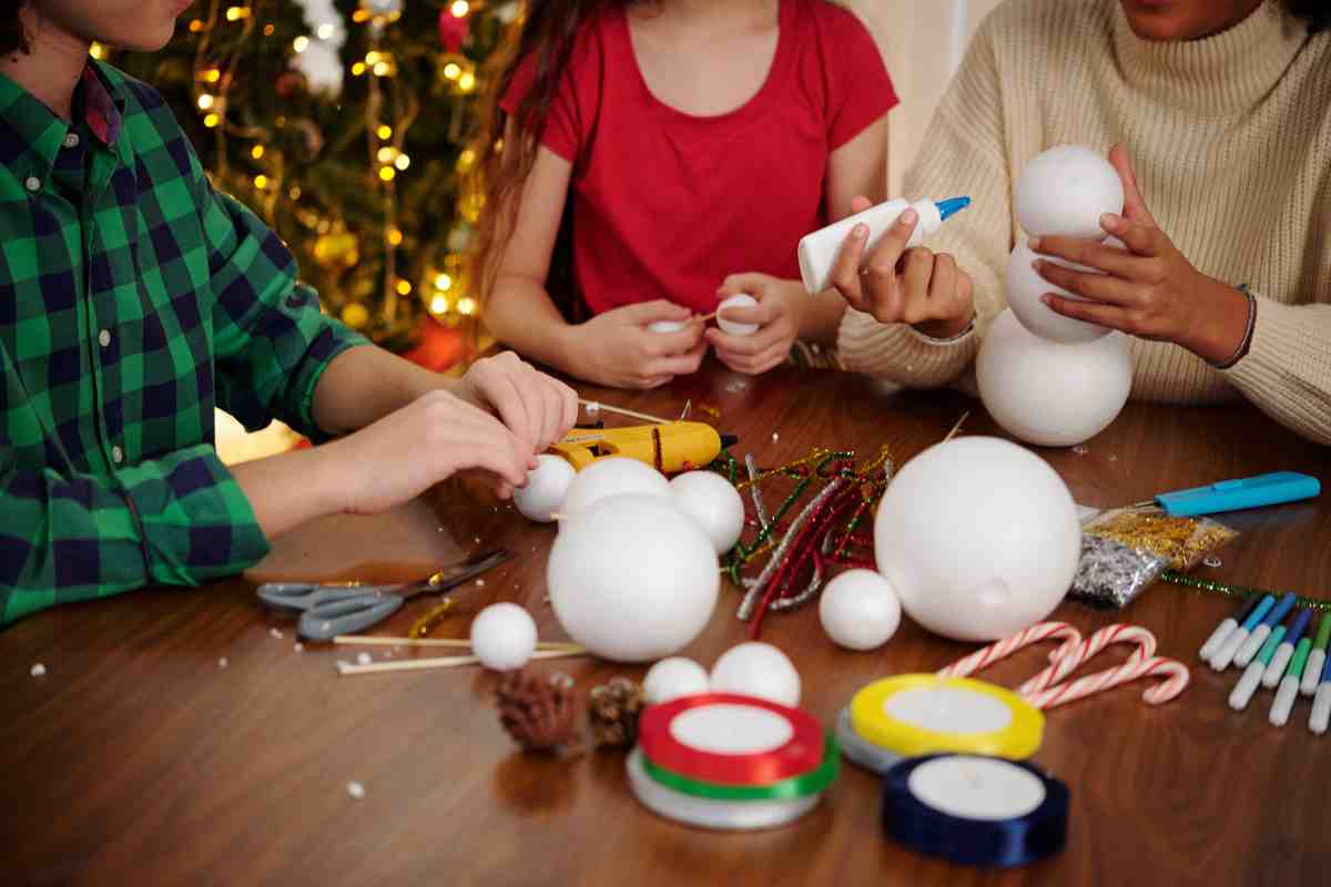 Bambini intorno al tavolo decorano le palline di polistirolo per Natale