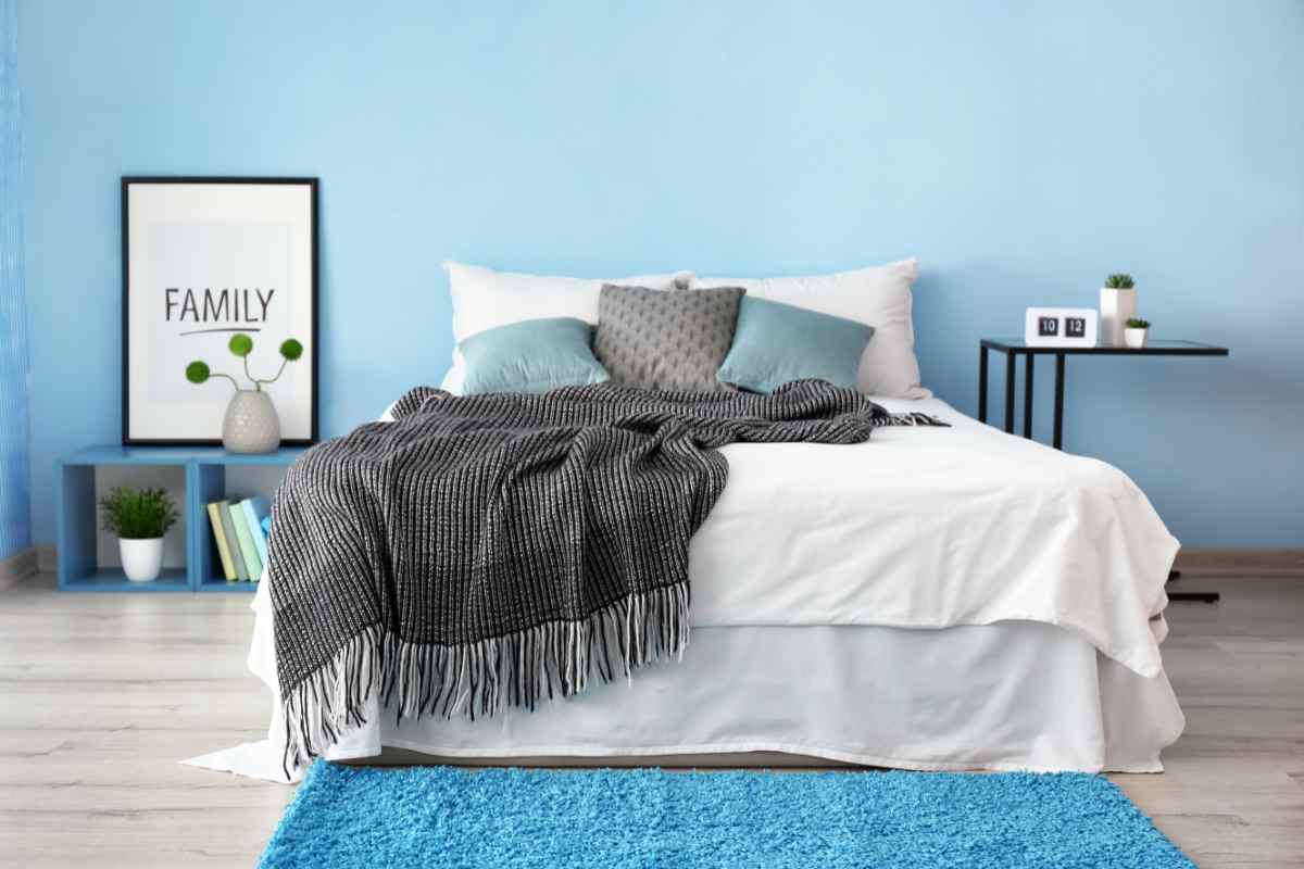 Camera da letto con tappeto e pareti color ciano