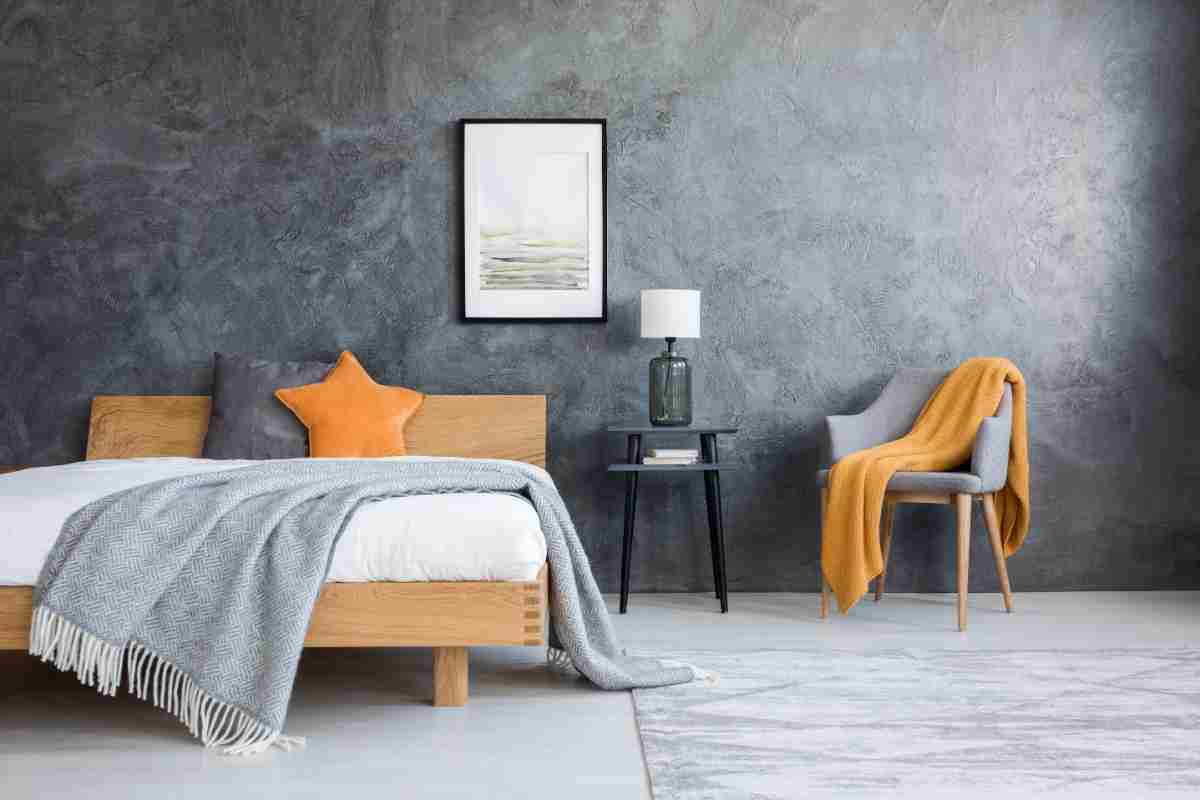 camera da letto con parete grigia, poltrona grigia e complementi arancione