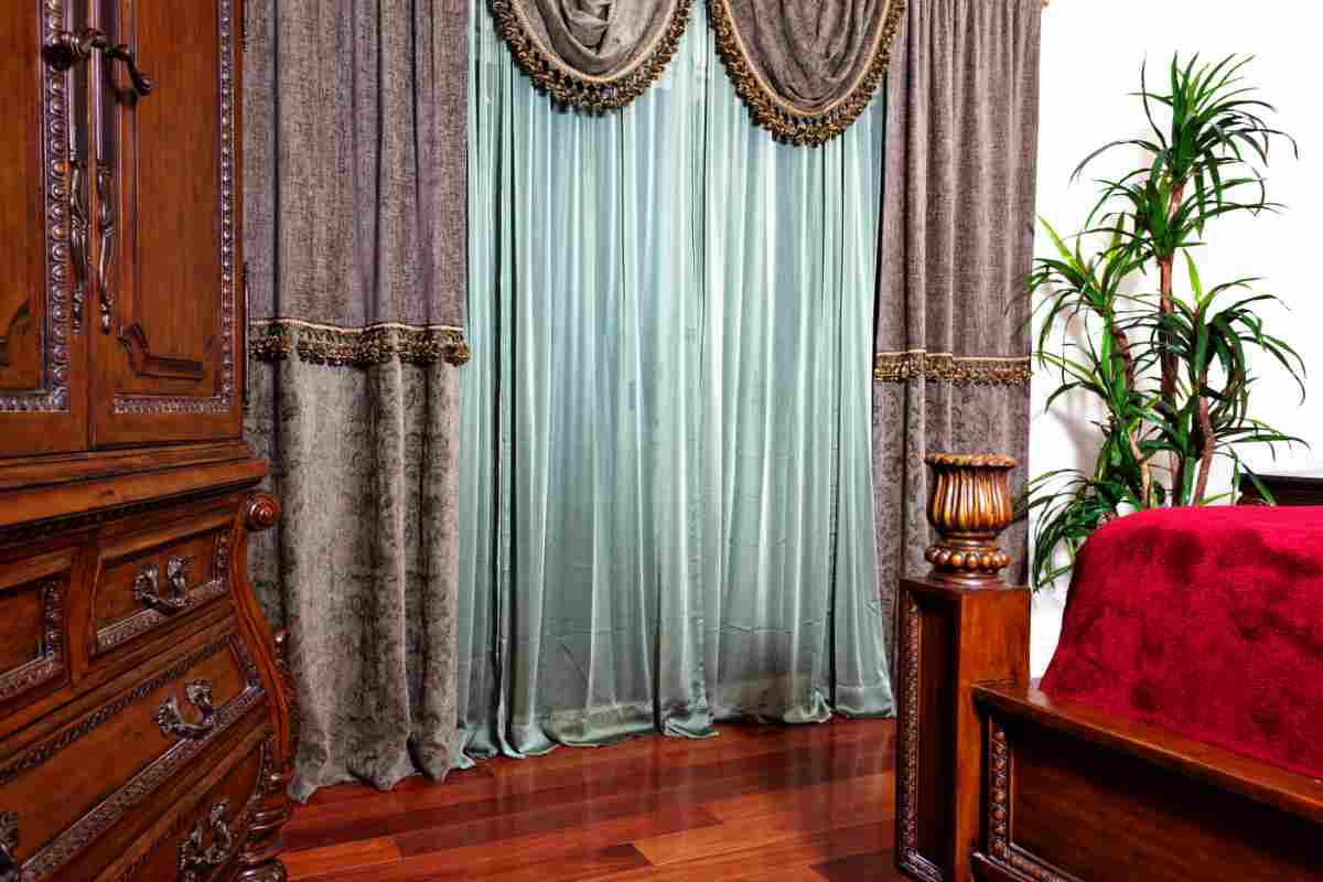 Camera da letto classica con mobili in legno massello con intarsi e tende di velluto