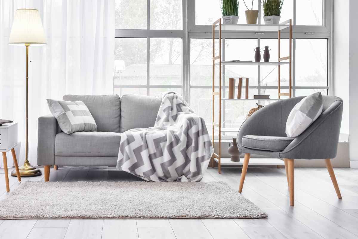 soggiorno con divano griglio e poltroncina con gambe in legno e seduta in tessuto grigio scuro