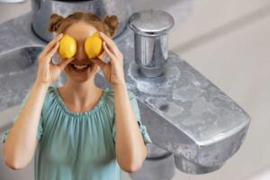Donna con i limoni in mano, rubinetto pieno di calcare
