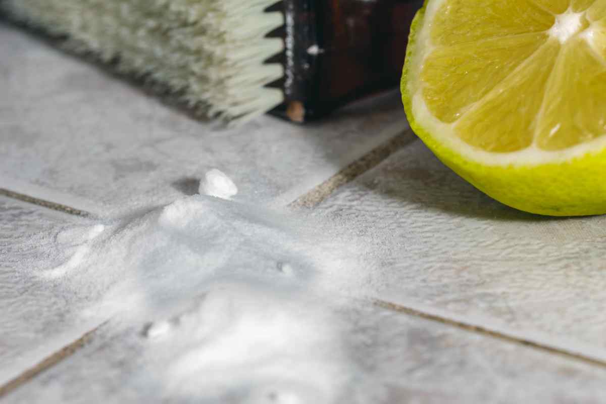 primo piano di bicarbonato e mezzo limone sulle piastrelle tra le fughe