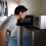 Ragazzo apre il forno a microonde e guarda al suo interno
