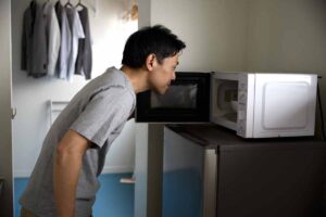 Ragazzo apre il forno a microonde e guarda al suo interno