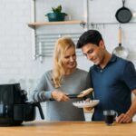 coppia che cucina vicino a friggitrice ad ria