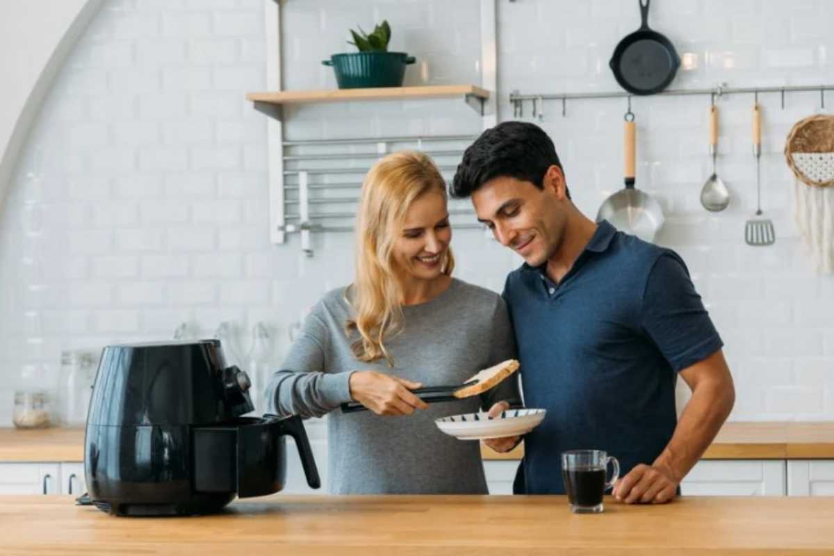 coppia che cucina vicino a friggitrice ad ria