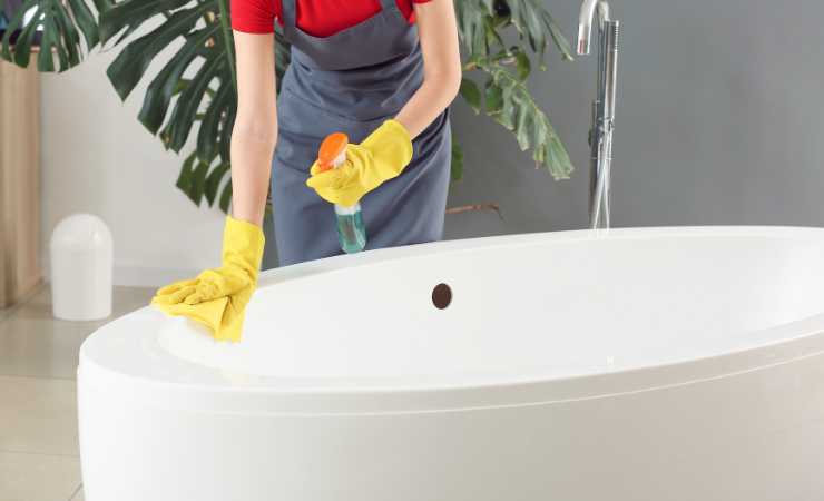 Donna che pulisce la vasca da bagno