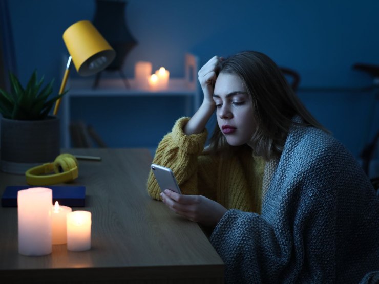 Donna al buio con candele e cellulare