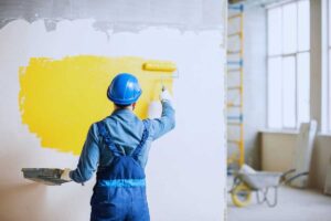 un operaio tinteggia di giallo il muro