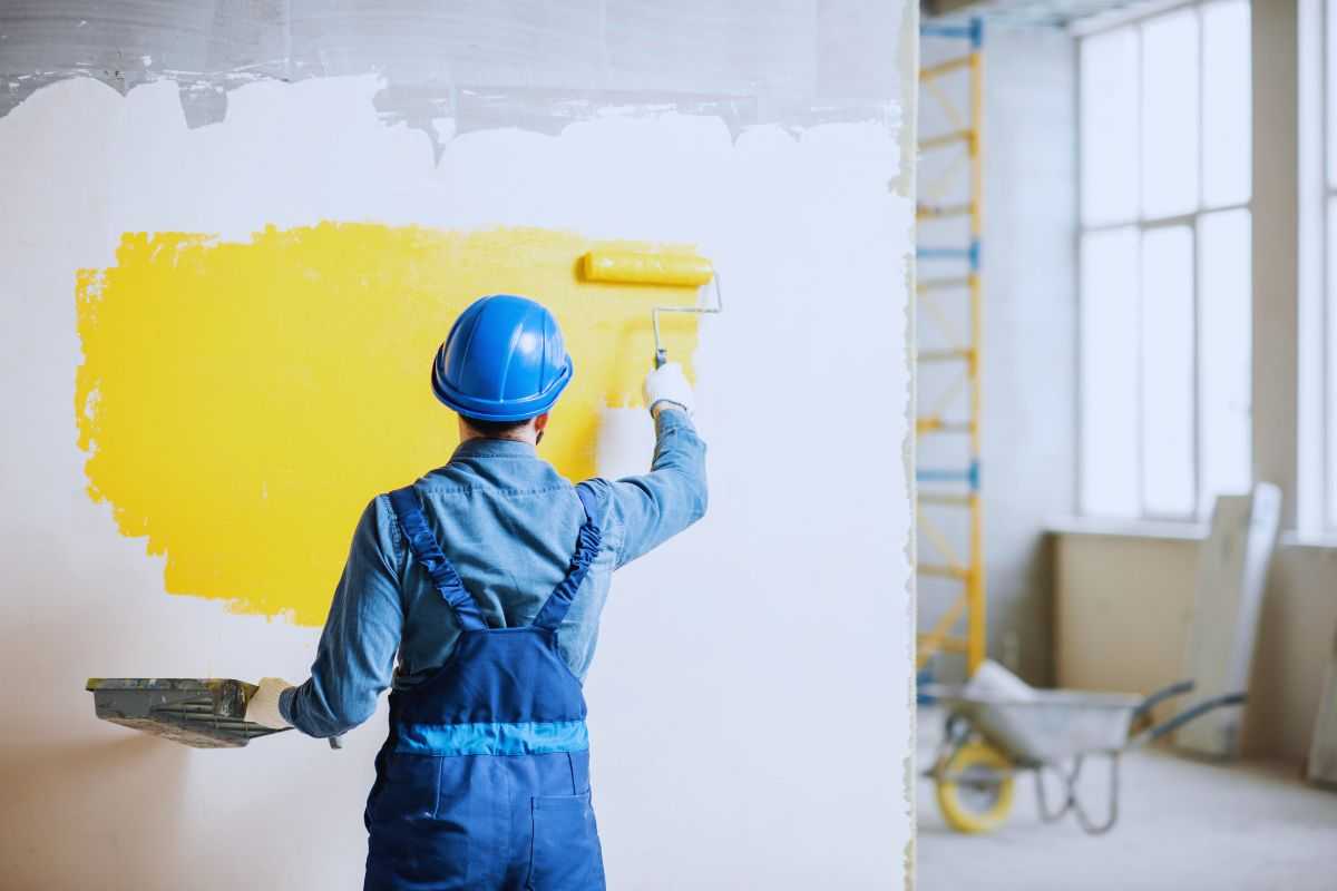 un operaio tinteggia di giallo il muro