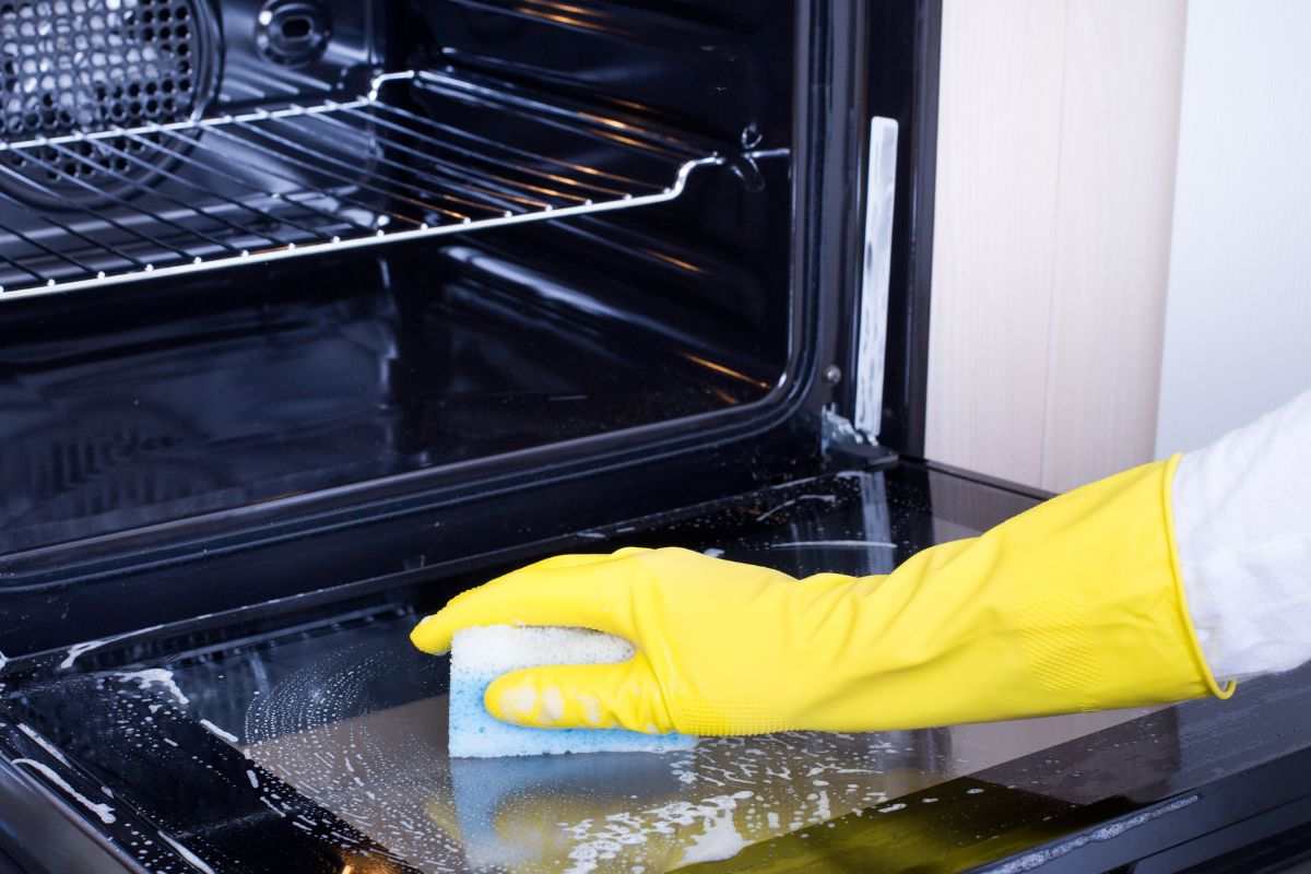 Mano che pulisce il forno