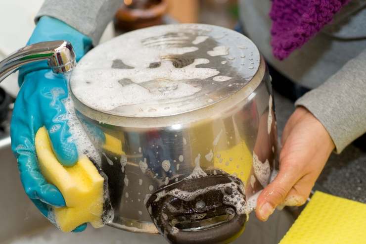 donna che pulisce pentola con sapone e spugnetta