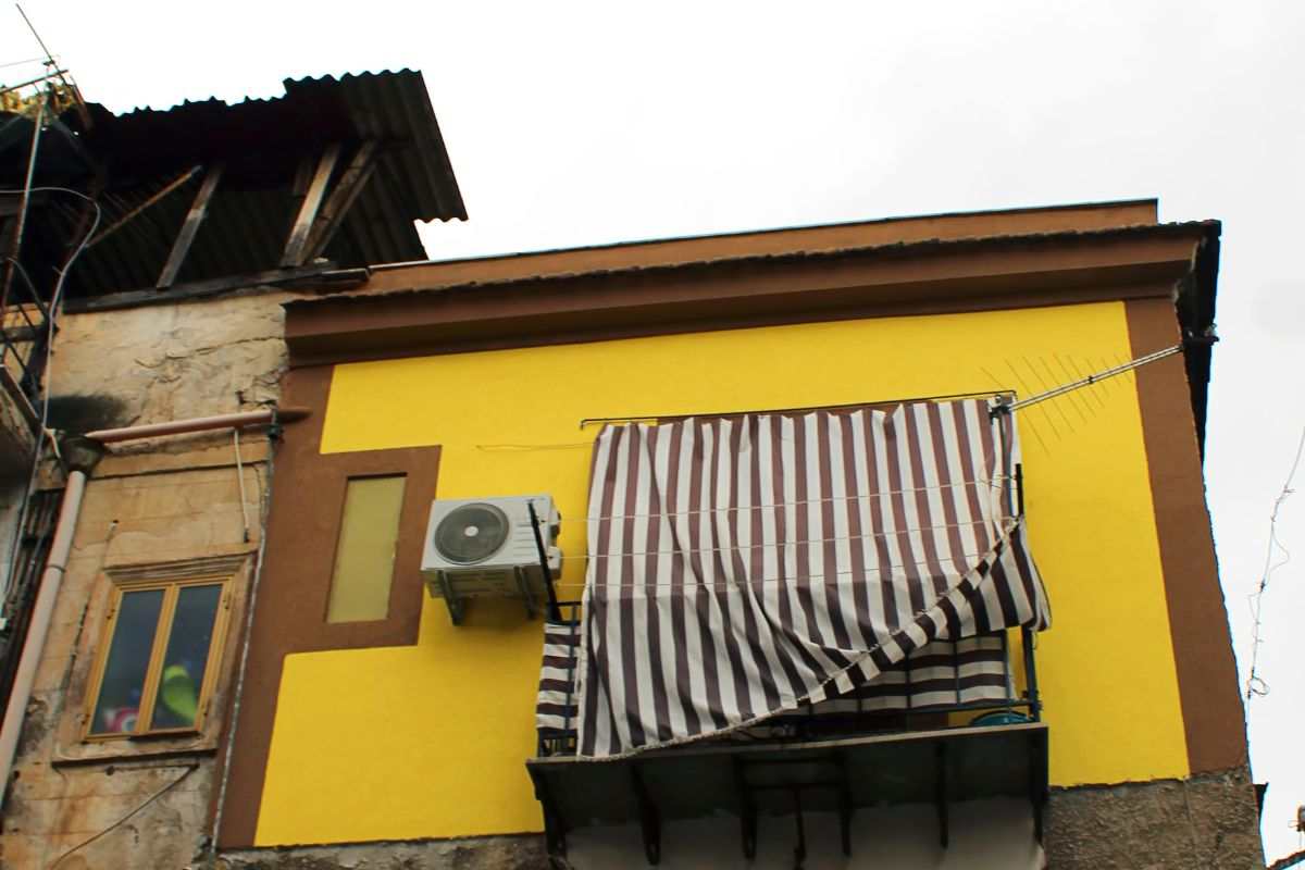 Tende parasole lunga aperta su casa con muri esterni gialli