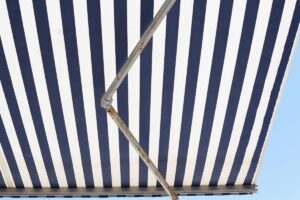 Tende da sole bianca e blu aperta con ruggine su staffa