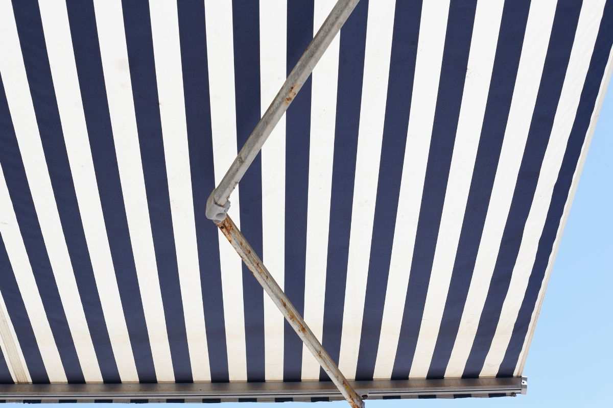 Tende da sole bianca e blu aperta con ruggine su staffa
