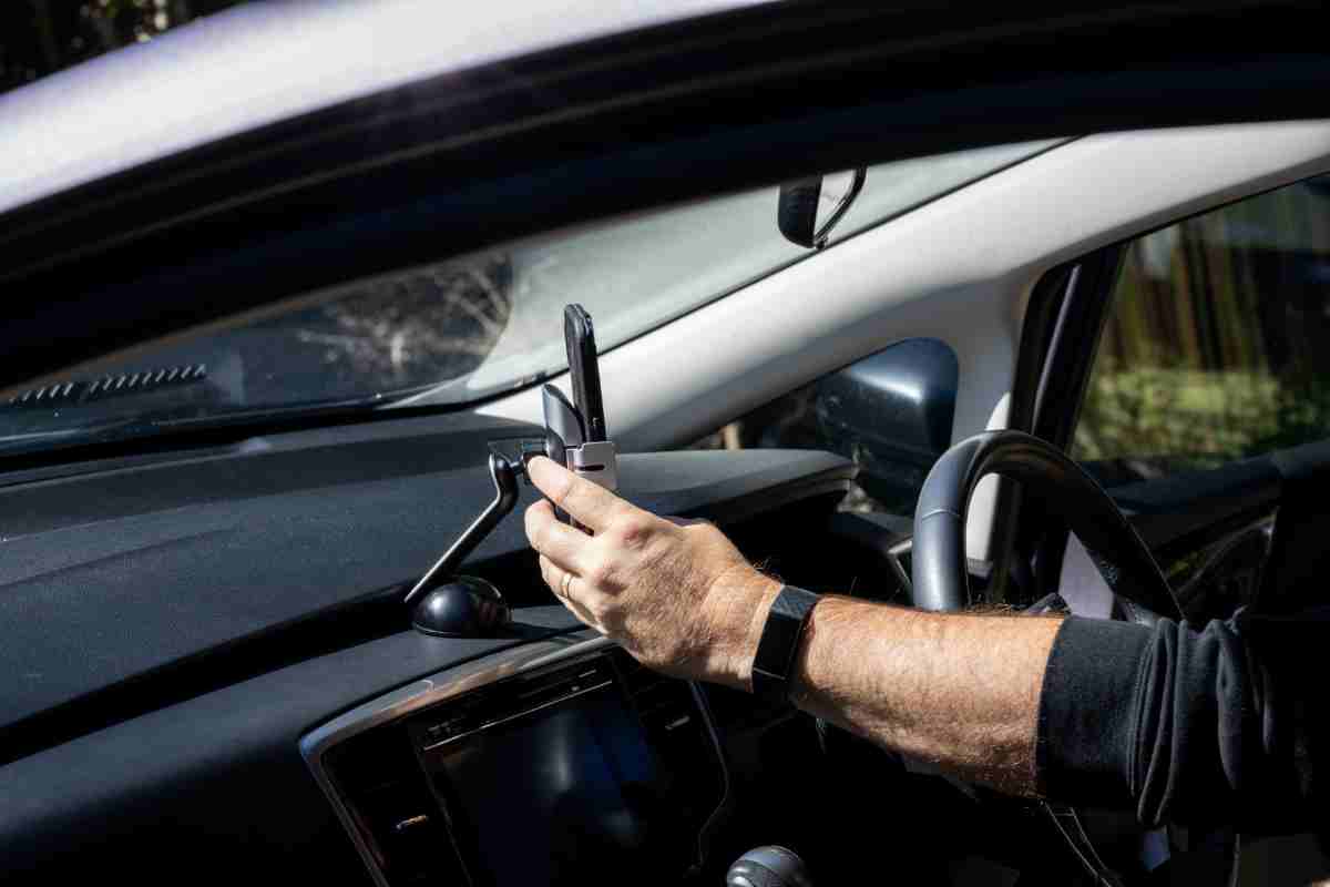 Înmânați pe telefonul mobil plasat pe încărcătorul wireless universal pentru mașină