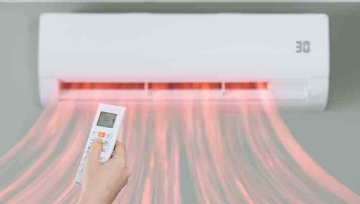 aria che esce da condizionatore e mano con telecomando
