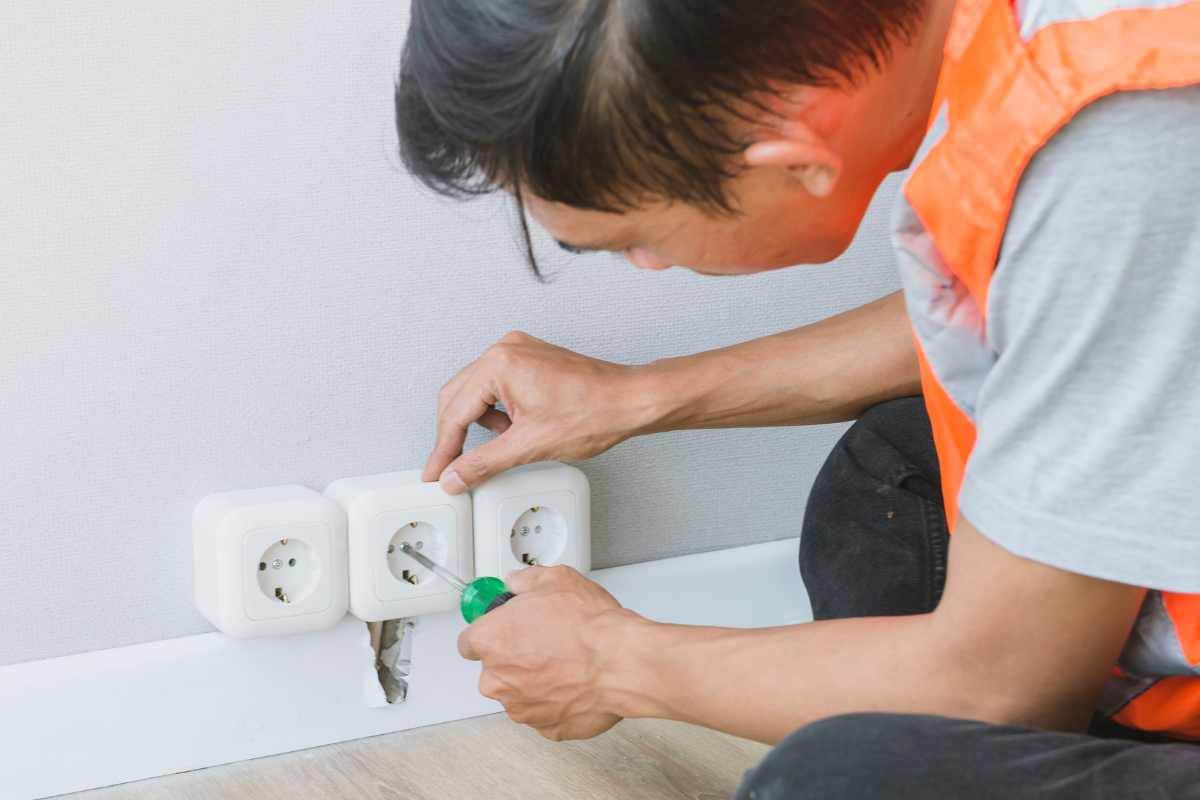Persona che sistema una presa elettrica