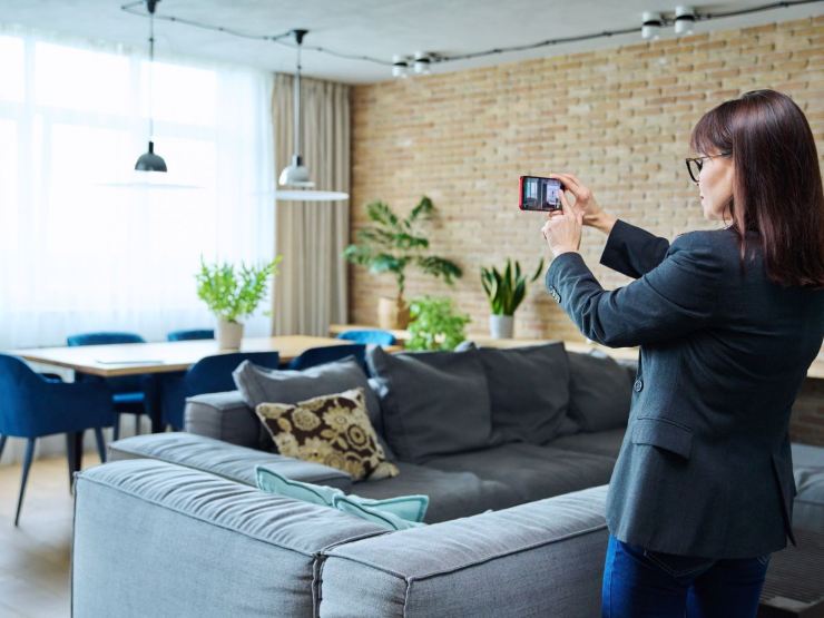 Donna che fotografa una casa e nello specifico un soggiorno
