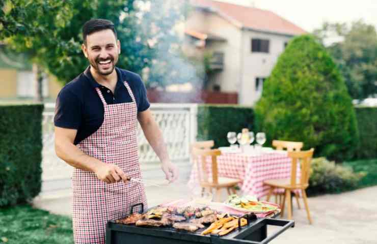 uomo fa il Barbecue in giardino