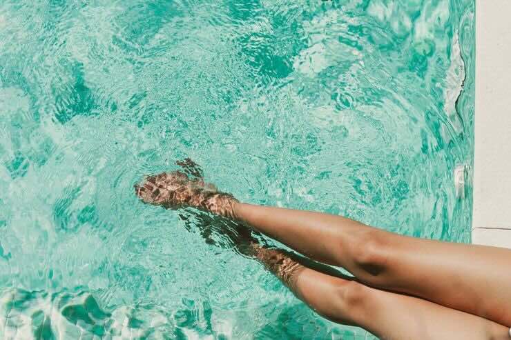 Gambe nell'acqua della piscina 