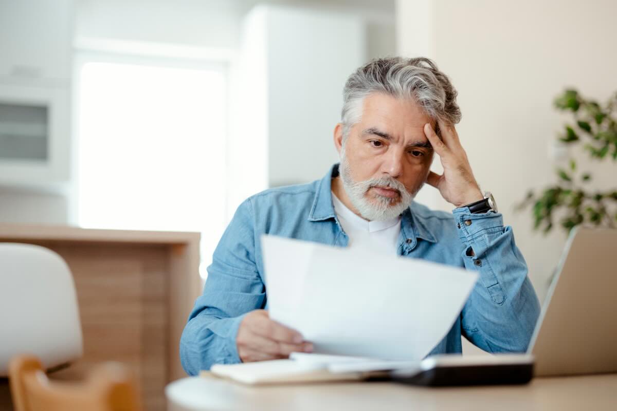 uomo che legge foglio preoccupato