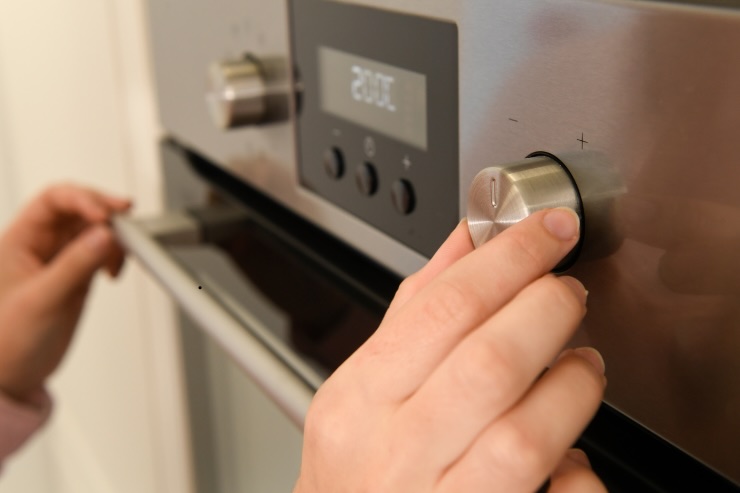 mani che impostano il forno toccando le manopole