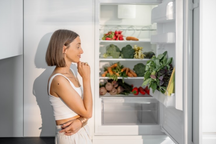donna che guarda cibi dentro il frigorifero