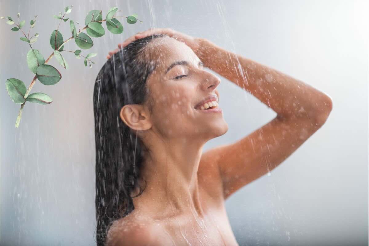 Ragazza fa la doccia felice, rametto di eucalipto