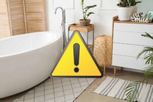 Bagno arredato con tappeti e simbolo attenzione