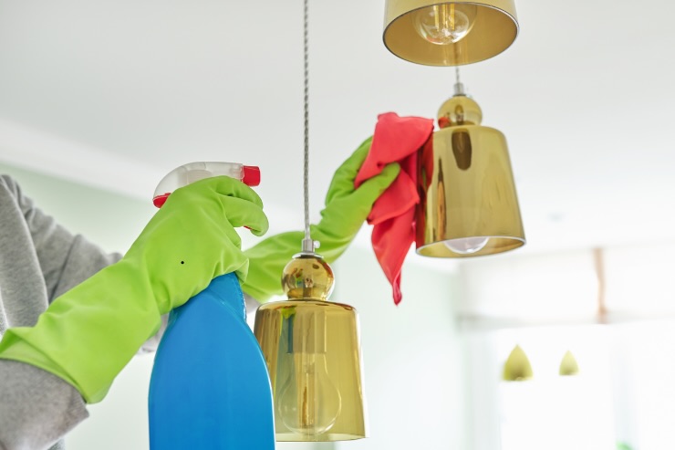 mano con spruzzino e panno sul lampadario