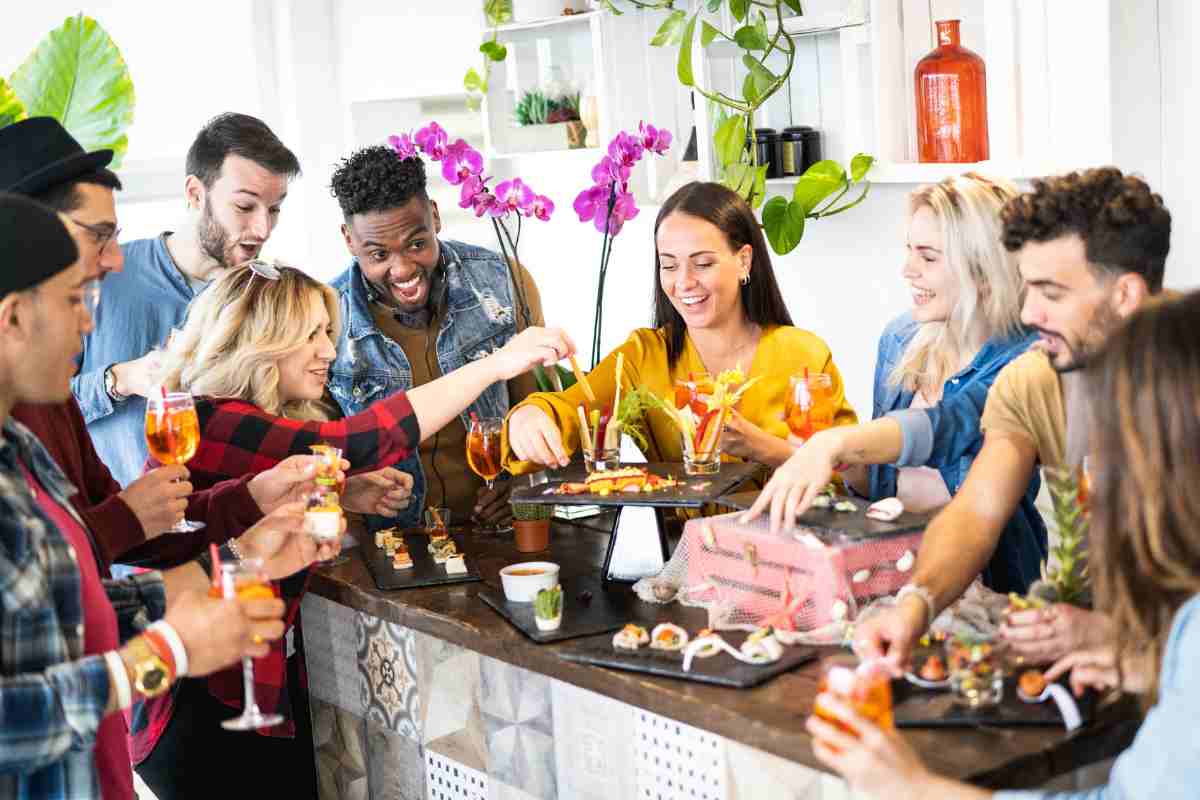 giovani intorno a un tavolo fanno aperitivo a casa con accessori ikea