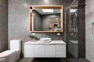 Bagno in grigio con uno specchio in legno