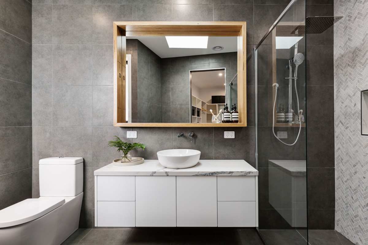 Bagno in grigio con uno specchio in legno